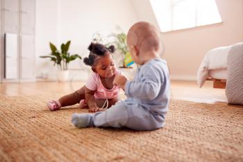 Baby Boy And Girl Playing With Toys On Rug At Home Together