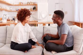 Young Couple Relaxing On Sofa At Home Talking Together