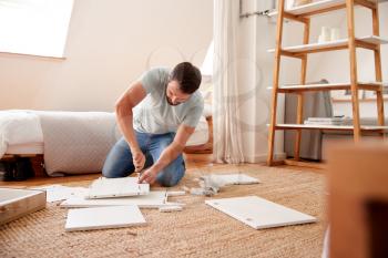 Man In New Home Putting Together Self Assembly Furniture