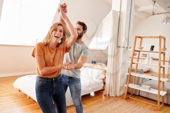 Couple Having Fun In New Home Dancing Together
