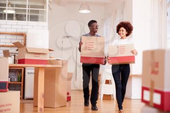 Smiling Couple Carrying Boxes Into New Home On Moving Day