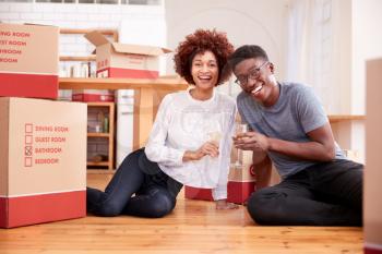 Portrait Of Couple Celebrating Moving Into New Home Drinking Champagne