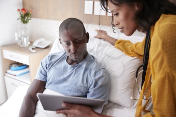 Doctor With Digital Tablet Visiting And Talking With Male Patient In Hospital Bed