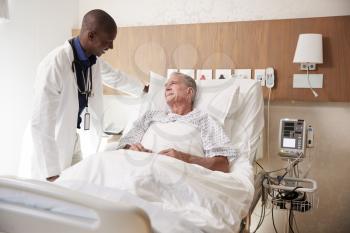 Doctor Visiting And Talking With Senior Male Patient In Hospital Bed