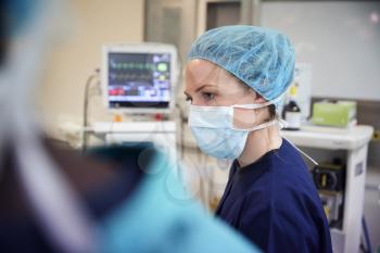 Female Surgical Team Member Working On Patient In Hospital Operating Theatre