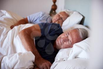 Senior white couple asleep in their bed, waist up, close up