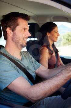 Smiling mid adult white couple driving in their car, close up, side view, vertical
