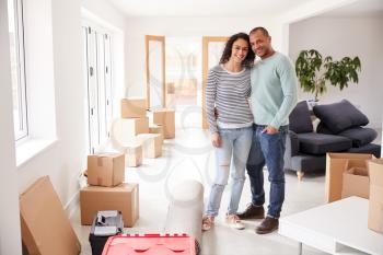 Portrait Of Loving Couple Surrounded By Boxes In New Home On Moving Day