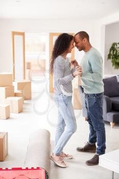 Loving Couple Surrounded By Boxes In New Home On Moving Day