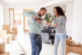 Couple Celebrating Moving Into New Home Opening Champagne