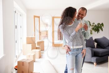 Couple Celebrating Moving Into New Home Drinking Champagne