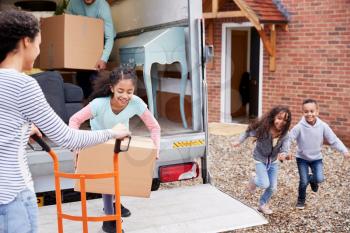 Family Unloading Furniture From Removal Truck Into New Home