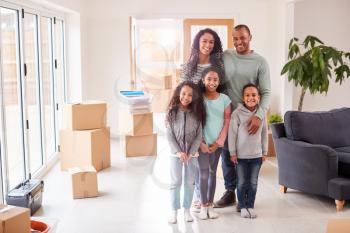 Portrait Of Family Surrounded By Boxes Standing In Room On Moving Day