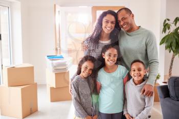 Portrait Of Family Surrounded By Boxes Standing In Room On Moving Day