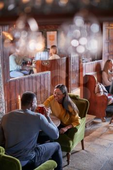 Couple Meeting For Lunchtime Drinks In Traditional English Pub Making A Toast