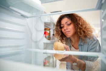 Disappointed Woman Looking Inside Refrigerator Empty Except For Potato On Shelf