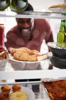 View Looking Out From Inside Of Refrigerator Filled With Takeaway Food As Man Opens Door