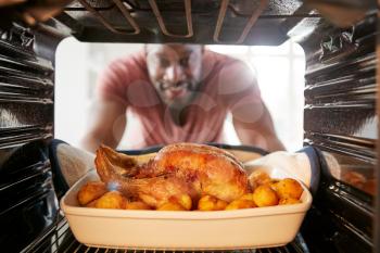 View Looking Out From Inside Oven As Man Cooks Sunday Roast Chicken Dinner