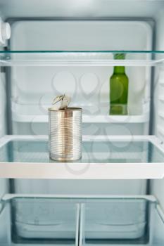 View Looking Inside Refrigerator Empty Except For Open Tin Can And Bottle Of Beer On Shelf