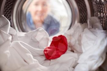 Woman Looking Inside Washing Machine With Red Sock Mixed With White Laundry