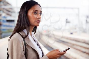 Businesswoman Standing On Railway Platform Commuting To Work Booking Ticket On Mobile Phone