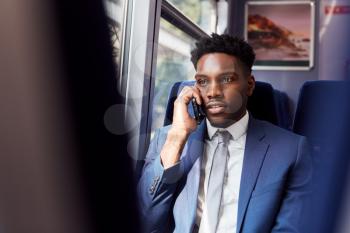 Businessman Sitting In Train Commuting To Work Making Call On Mobile Phone
