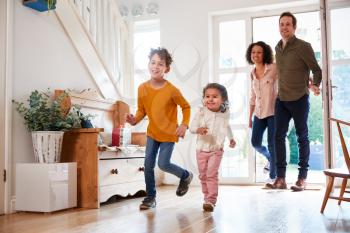 Family Returning Home After Trip Out With Excited Children Running Ahead