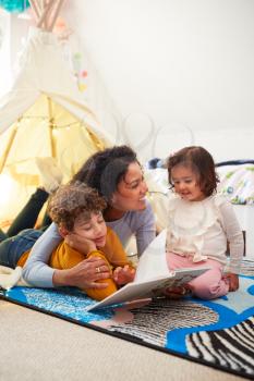 Single Mother Reading With Son And Daughter In Den In Bedroom At Home