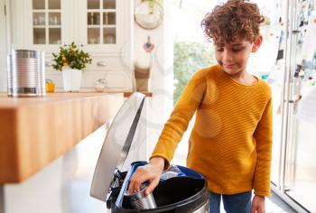 Boy Sorting Recycling Into Kitchen Bin At Home
