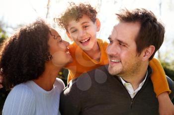 Outdoor Portrait Of Smiling Family In Garden At Home Against Flaring Sun