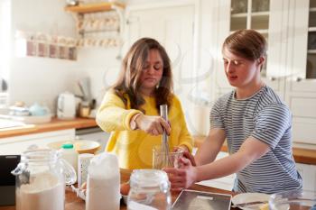 Young Downs Syndrome Couple Baking In Kitchen At Home