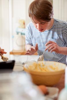 Young Downs Syndrome Man Baking Cupcakes In Kitchen At Home