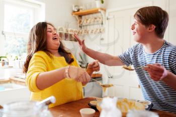 Young Downs Syndrome Couple Having Fun Baking Cupcakes In Kitchen At Home