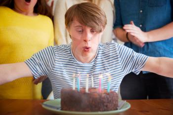 Young Downs Syndrome Man Celebrating Birthday At Home With Cake