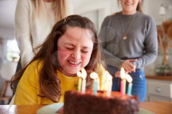 Young Downs Syndrome Woman Celebrating Birthday At Home With Cake