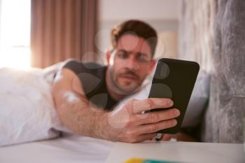 Man Waking Up In Bed Immediately Reaches Out To Look At Mobile Phone