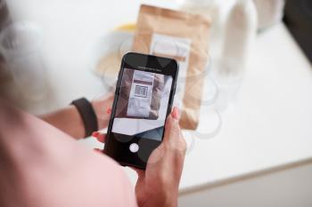Woman Wearing Fitness Clothing Scanning QR Code On Food Packaging To Find Nutritional Information