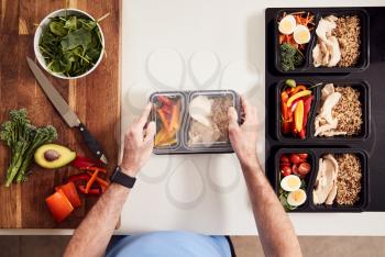Overhead Shot Of Man Preparing Batch Of Healthy Meals At Home In Kitchen
