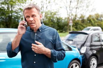 Mature Male Motorist Involved In Car Accident Calling Insurance Company Or Recovery Service