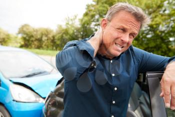 Mature Male Motorist With Whiplash Injury In Car Crash Getting Out Of Vehicle