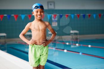 Portrait Of Boy Standing By Edge Of Swimming Pool Ready For Lesson