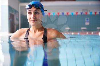 Female Swimmer Wearing Hat And Goggles Training In Swimming Pool