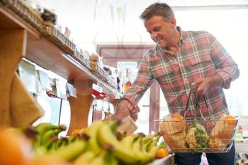 Male Customer With Shopping Basket Buying Fresh Produce In Organic Farm Shop