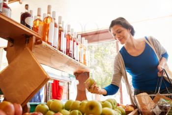 Female Customer With Shopping Basket Buying Fresh Apples In Organic Farm Shop