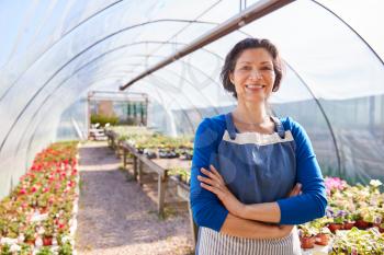 Portrait Of Mature Woman Working In Garden Center Greenhouse