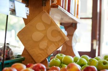Paper Bags Hanging Over Fruit And Produce Displayed In Organic Farm Shop