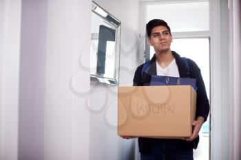 Male College Student Carrying Box Moving Into Accommodation