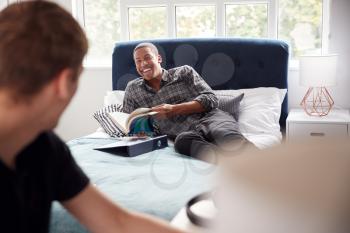 Two Male College Students In Shared House Bedroom Studying Together