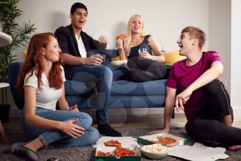 Group Of College Students In Shared House Having Night In Eating Pizza Together