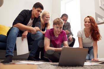 Group Of College Students In Lounge Of Shared House Studying Together